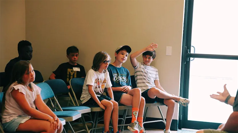 Students in a class. One boy raising hand.