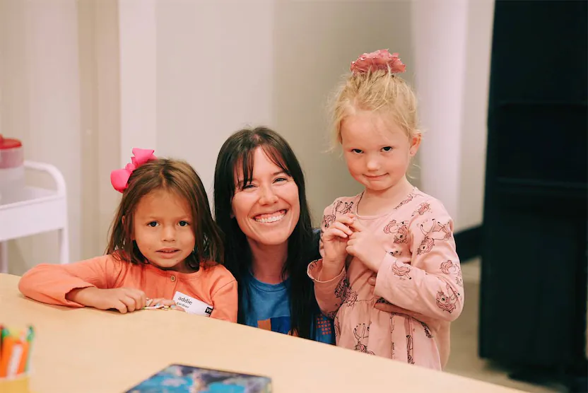 Teacher smiling with to kids.