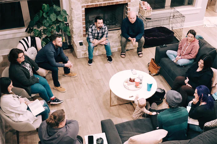 People in a living room sitting in a circle while talking.